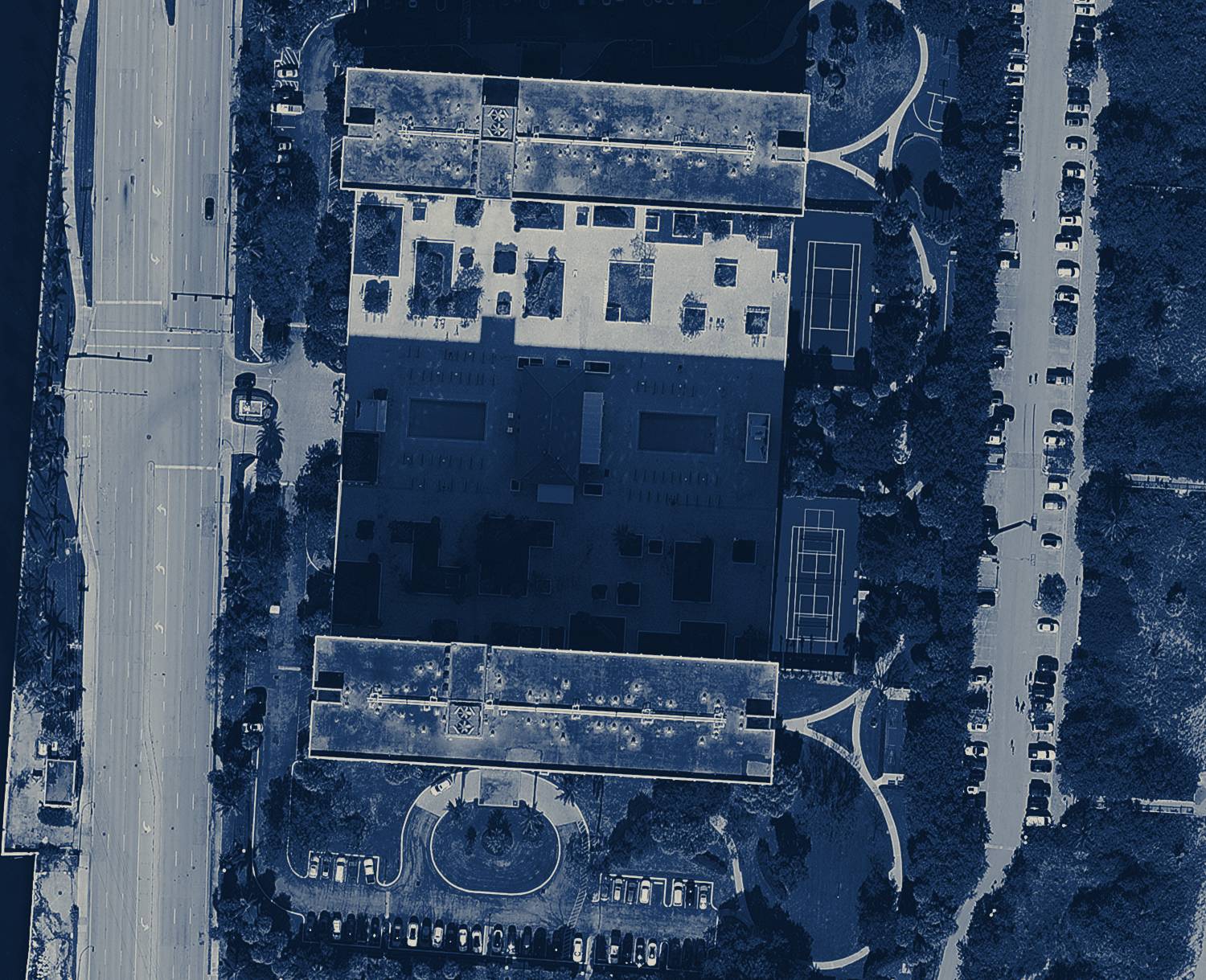 Navy-toned aerial view of an oceanfront Florida condominium and its roofs